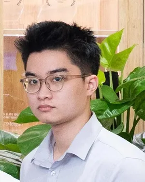 Đức in a light grey shirt at the HDBank and Savyu signing ceremony, beside a potted plant.