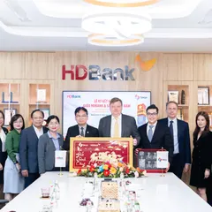 Thirteen people in HDBank's meeting room at the signing ceremony; the group in the middle holds a framed painting and a gift box.