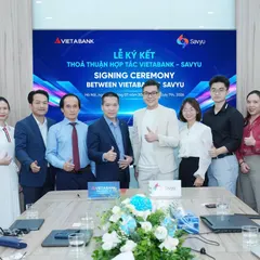Eleven people from VietABank and Savyu at the signing ceremony, most giving a thumbs-up in front of the ceremony screen.